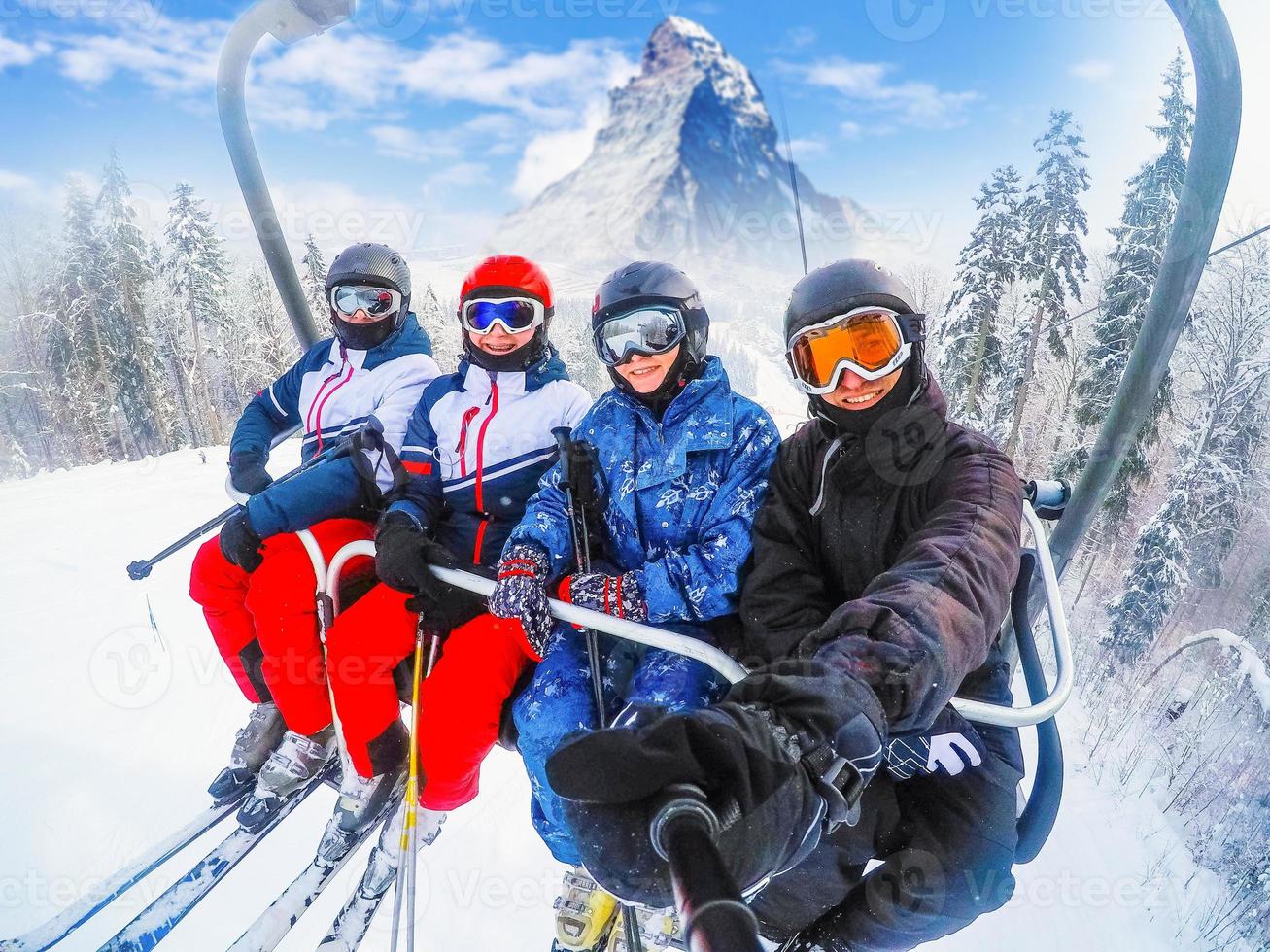 amazing beautiful view ski resort in Switzerland with cable chairlift transport Cheerful young friends skiers on ski lift photo