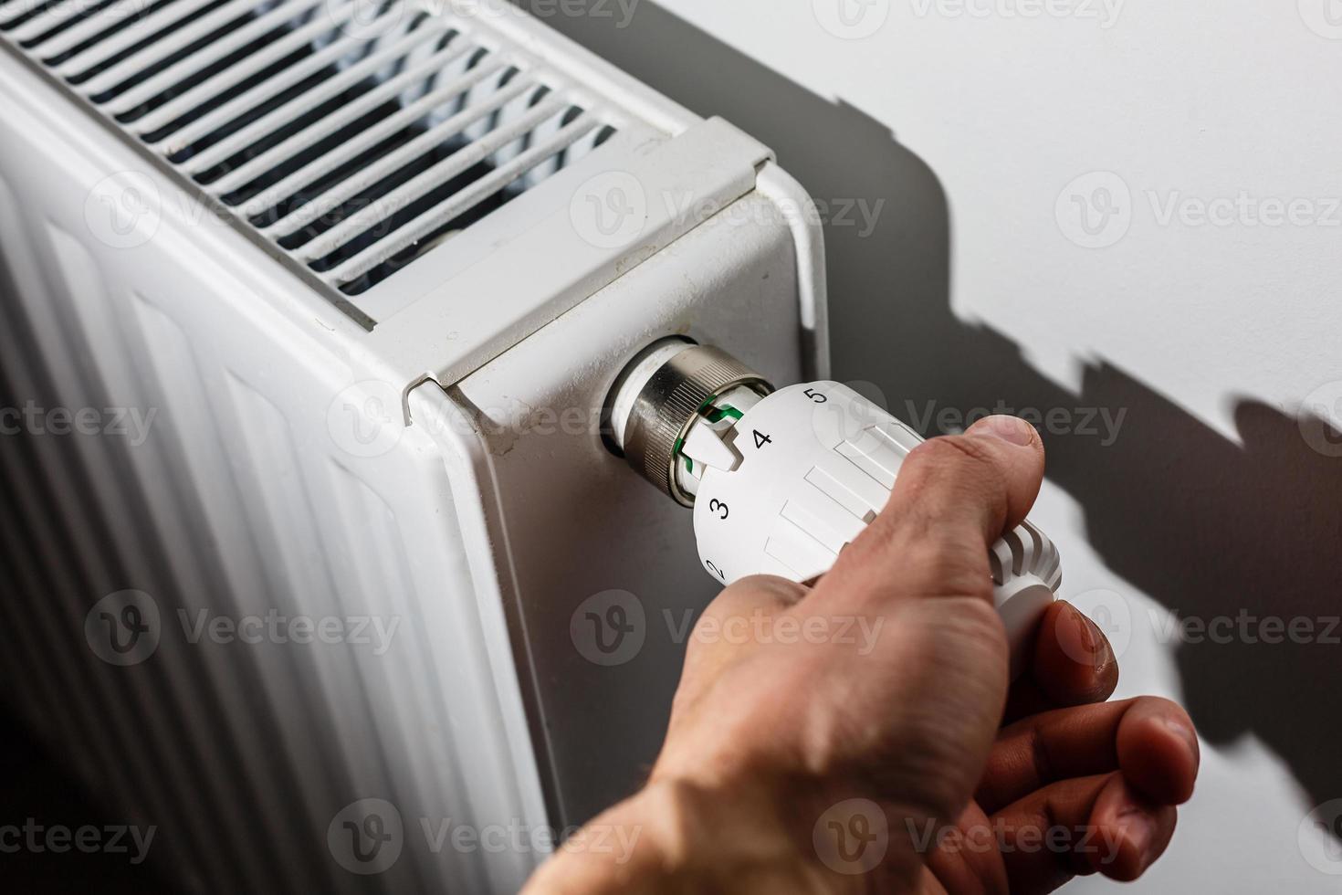 primer plano de la mano ajustando el termostato de calefacción foto