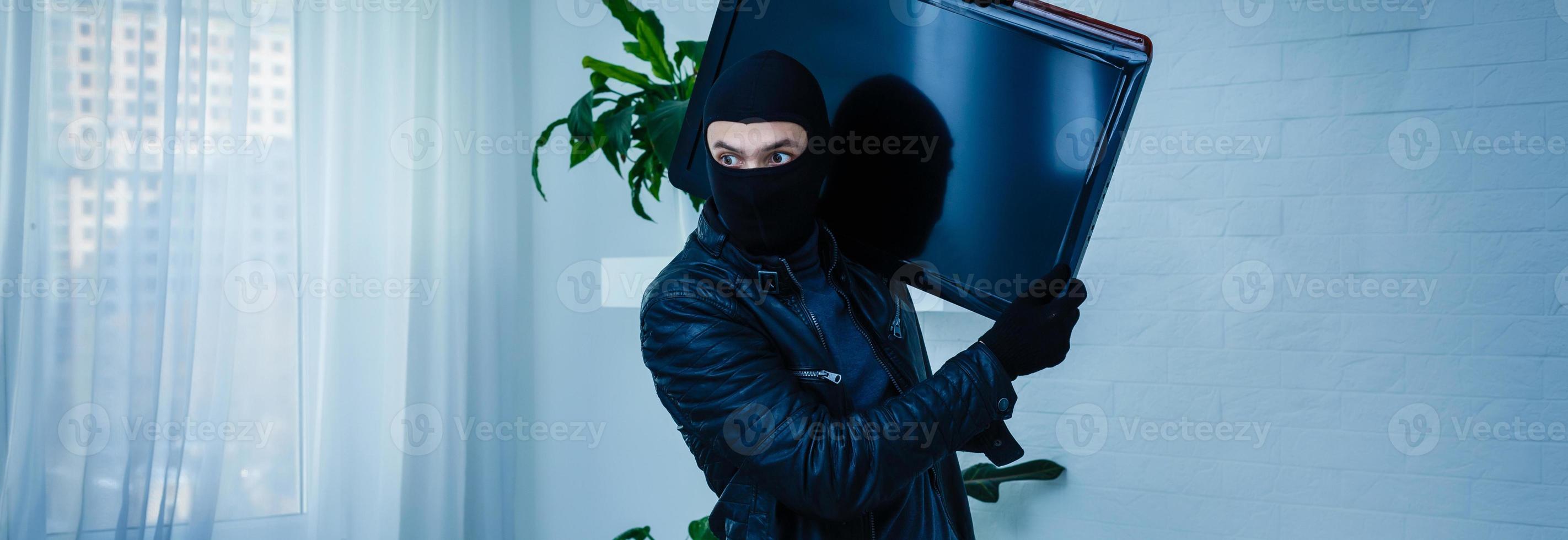 hombre ladrón robando televisor de casa foto