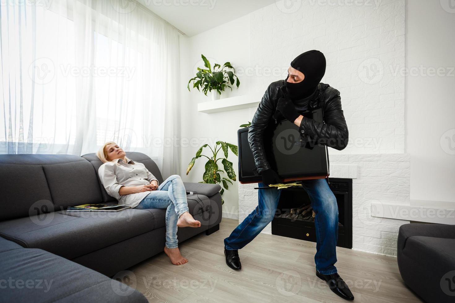 Robber man dressed in black hoodie stands with disguised face and holds a lot of money in his hands, stole a large amount, a thief man stole a TV photo