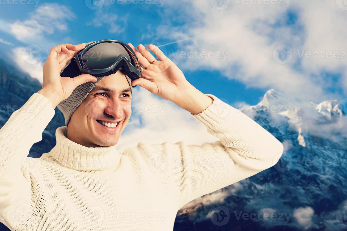 Portrait of young man in sunglass mask, ski resort on the background of mountains and blue sky photo