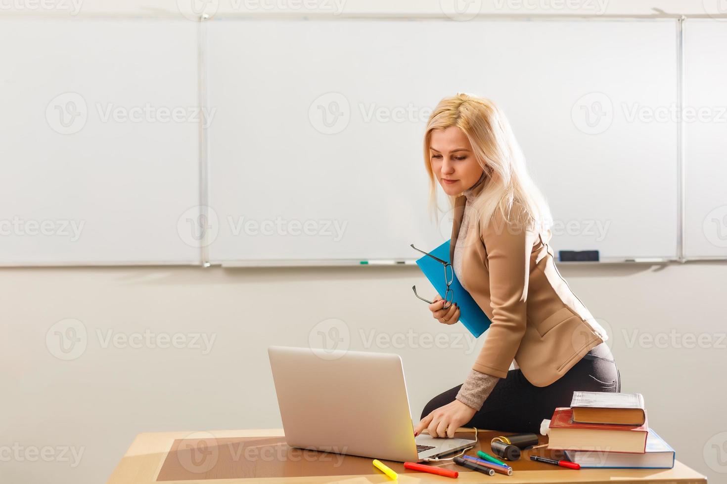 E-Learning concept with student holding his modern laptop computer, Tutor needs to be enthusiastic and needs to like his subject, Teacher drawing at classroom in school, photo