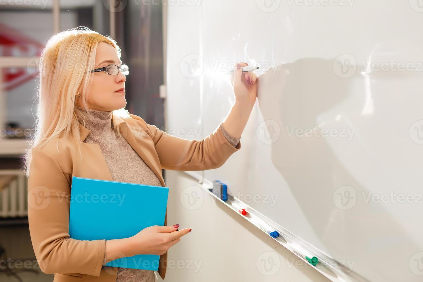 bastante joven estudiante universitario escribiendo en la pizarra, pizarra durante una clase de matemáticas foto