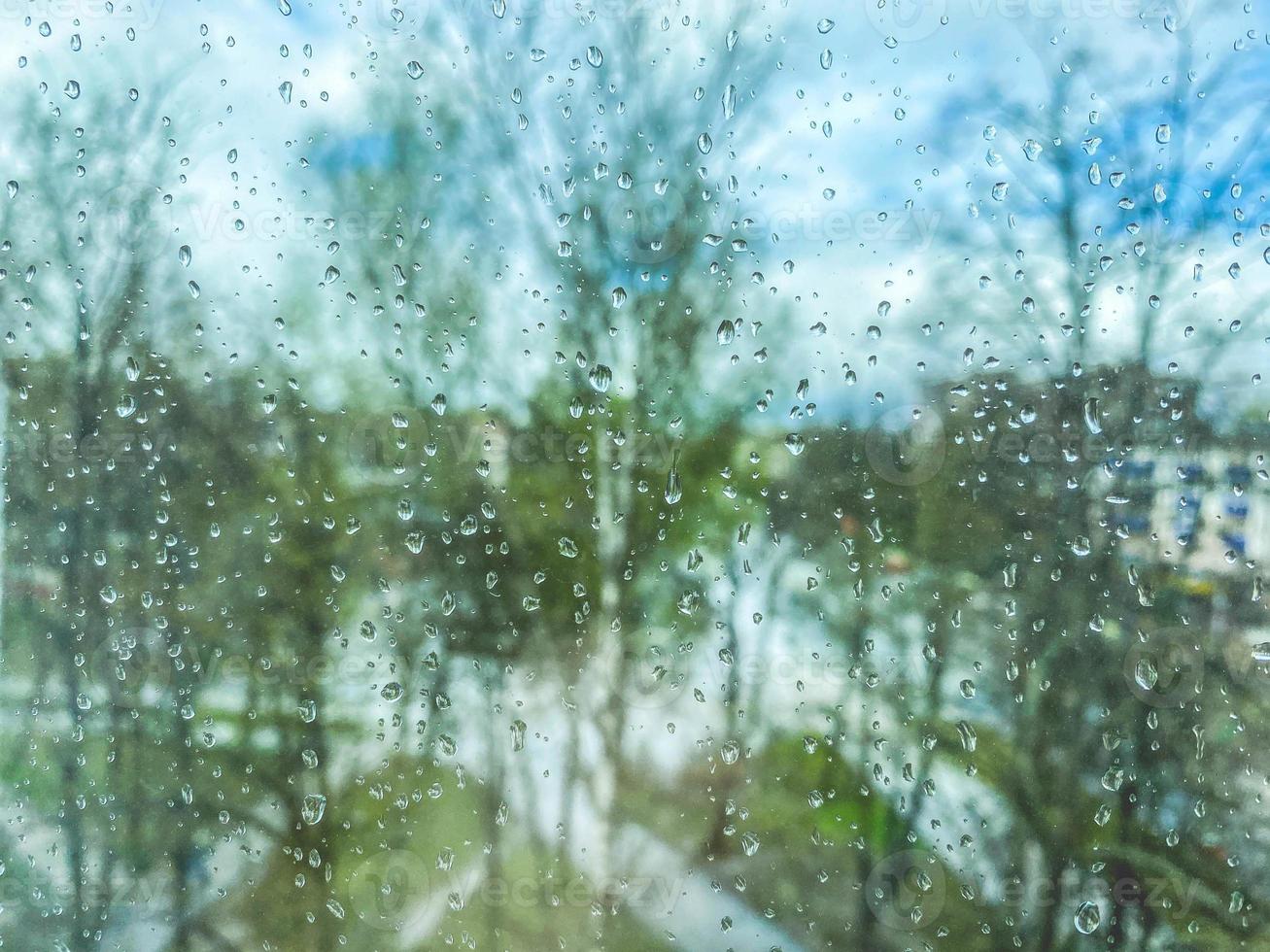 reflection in glass, window of a multi-storey building. raindrops on the glass. texture, background. against the backdrop of trees, plants and greenery in the rain photo