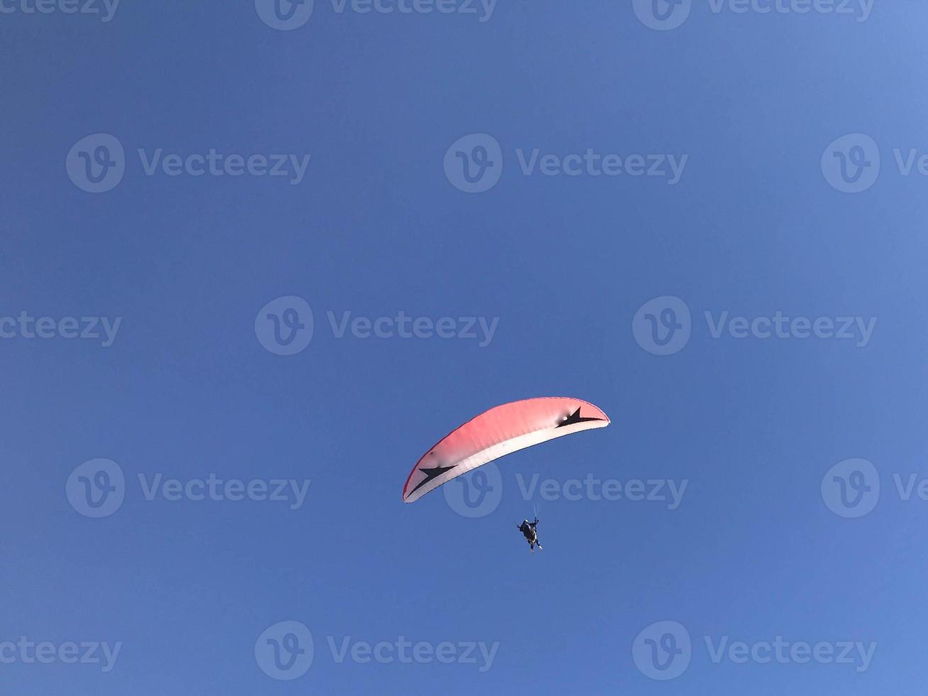 Skydiver and colorful parachute on blue sky background photo