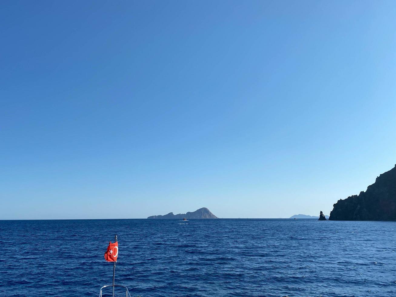 The waving Turkish flag on a calm sea background with a boat and blue sky photo