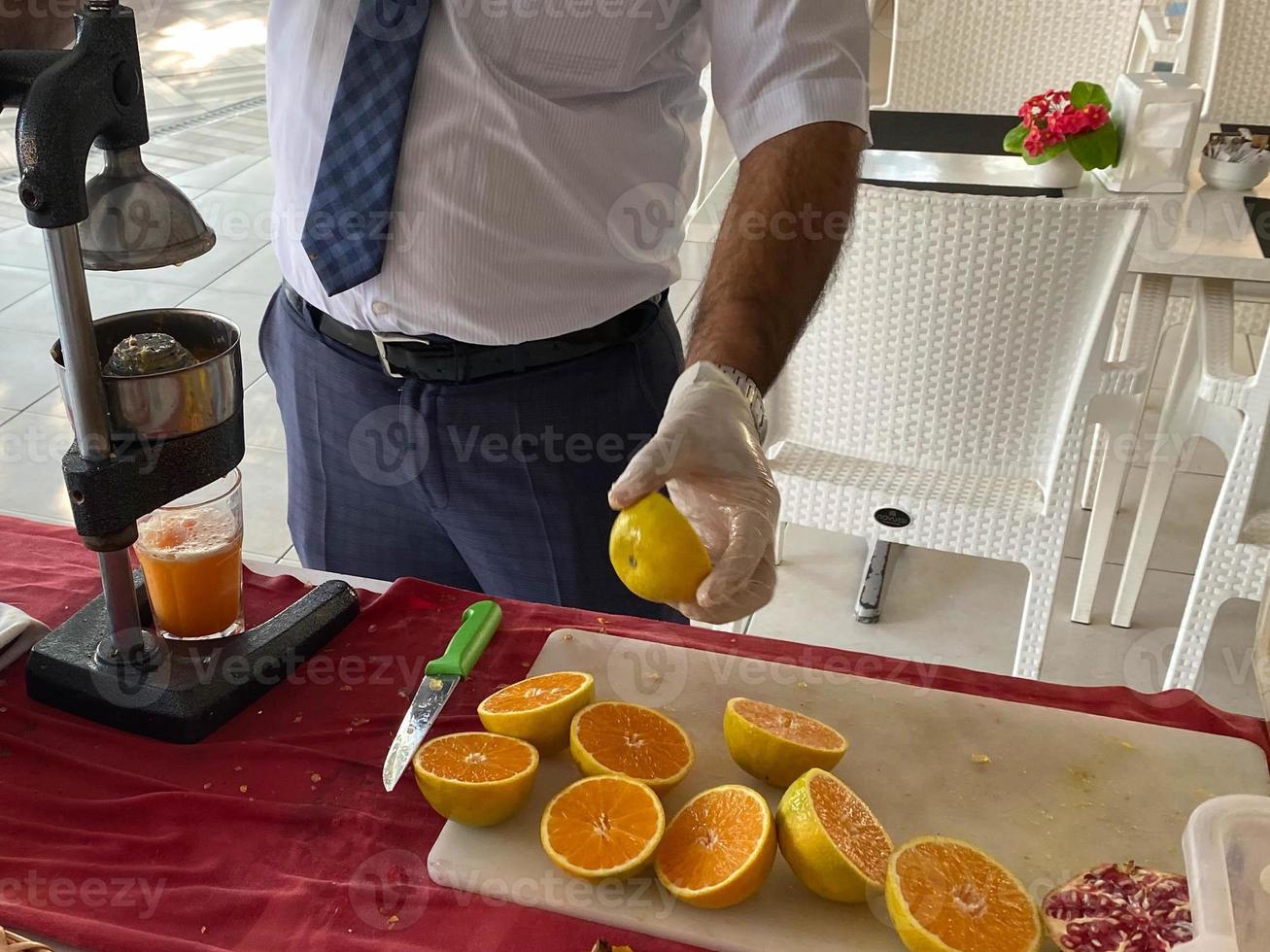 A man makes freshly squeezed orange juice with a manual juicer at an all-inclusive hotel in a touristic warm tropical country paradise resort on vacation photo