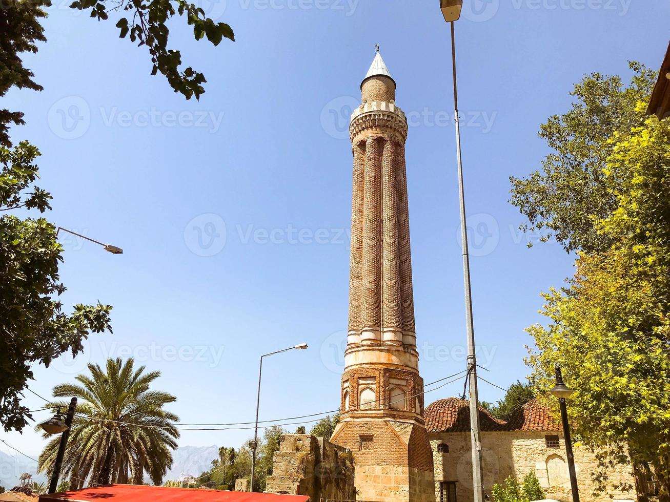 area in a hot, tropical country. small houses with tiled roofs against the backdrop of green palm trees. in the center of the square there is a high tower with a spire photo