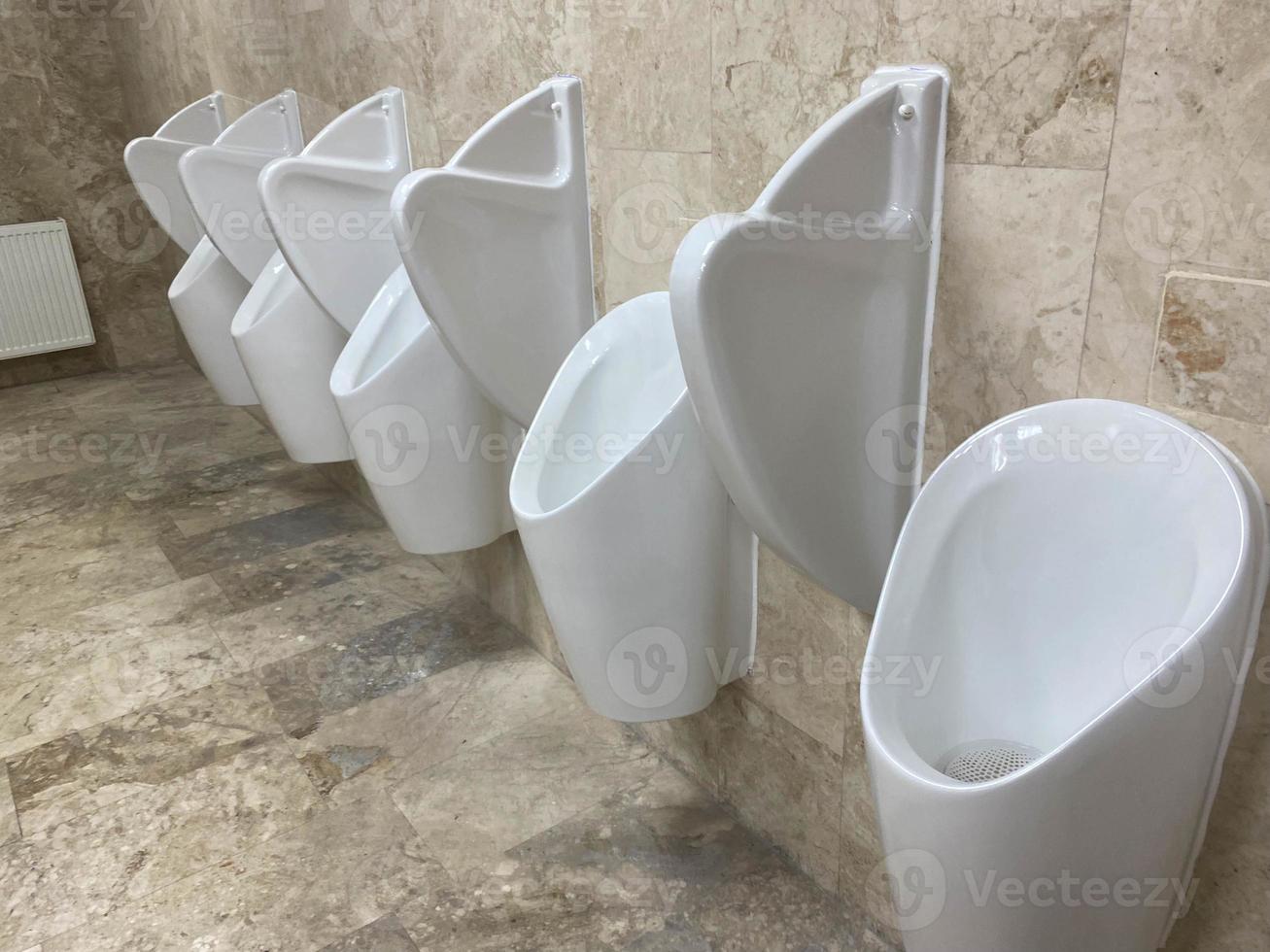 A Row Of Urinals In Tiled Wall In A Public Restroom photo