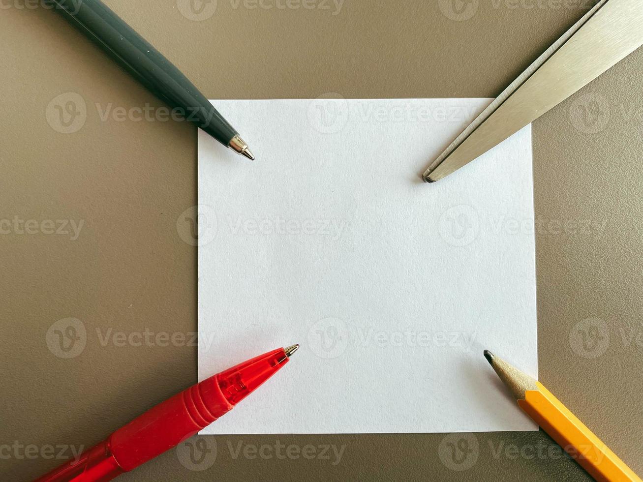 papelería en la mesa de la oficina. bolígrafos y lápices para escribir, tijeras de papelería se encuentran en papel de nota foto