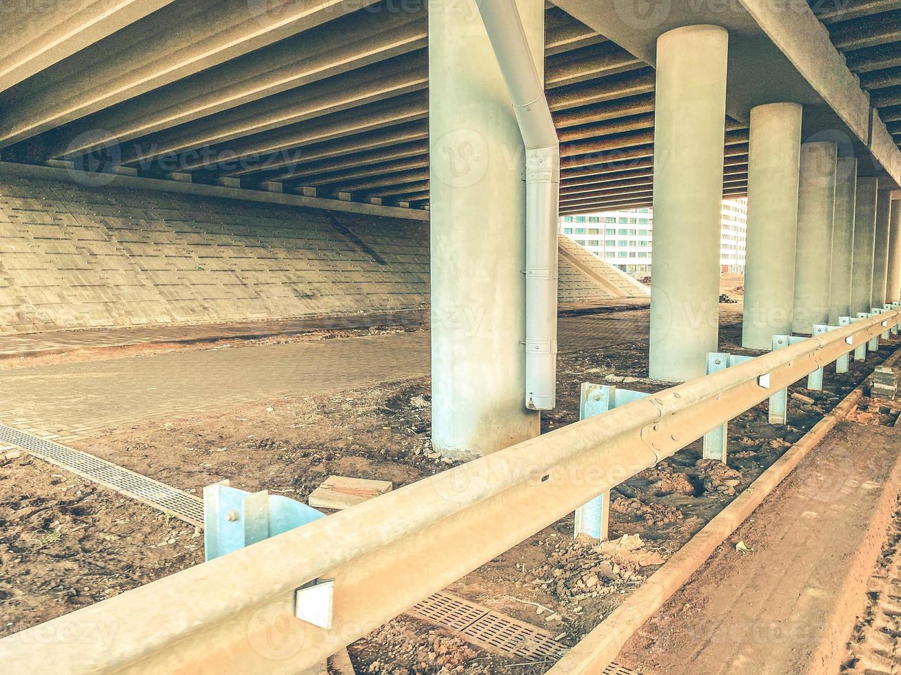 place under the bridge. bridge made of concrete on beams, reliable construction. next to the bridge protective structures, additional elements for cars photo