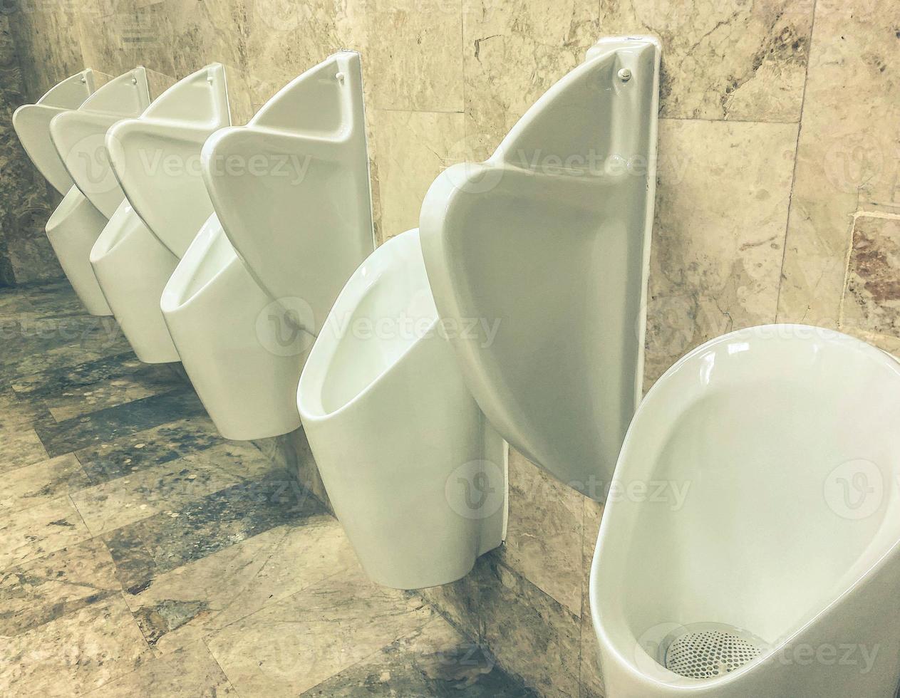 men's toilet. white faience urinals are fixed on the wall. going to the toilet while standing. relief of need. plumbing inventory photo