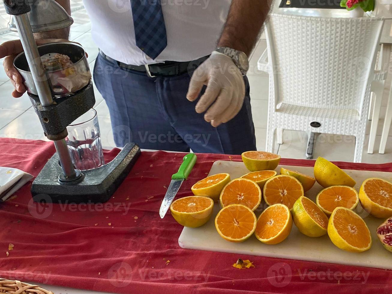 A man makes freshly squeezed orange juice with a manual juicer at an all-inclusive hotel in a touristic warm tropical country paradise resort on vacation photo
