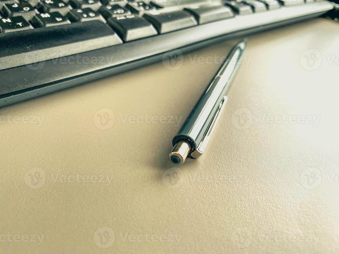 stationery on the table in the office. blue, small pen with a rod for making notes on paper. metal pen for writing. next to the keyboard for typing photo