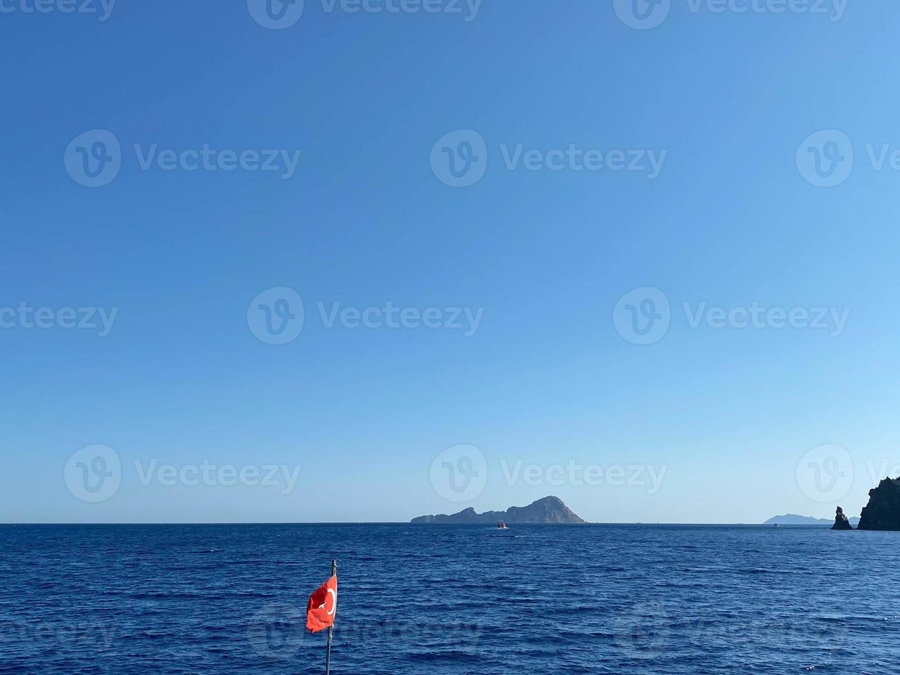 Turkish flag on the background of the sea and mountains in sunny weather photo