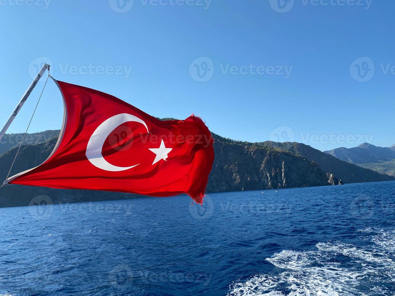 Close-Up Of Flag Of Turkey Waving Over Sea Against Clear Sky photo