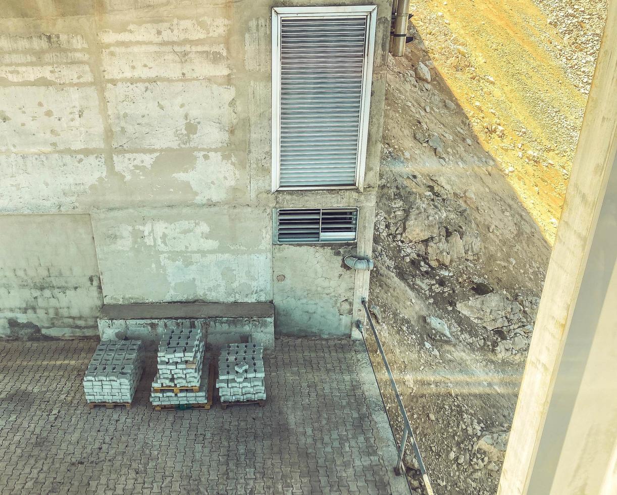 vista de los materiales de construcción desde arriba. los ladrillos de asfalto gris se apilan en la esquina de la casa. material de hormigón para la construcción de carreteras y bordes de carreteras foto