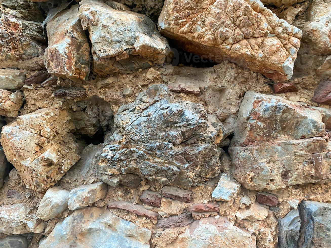 Background, texture, stone wall of round stones cobblestones bricks natural surface natural sharp convex rough stone cobblestone with cracks photo