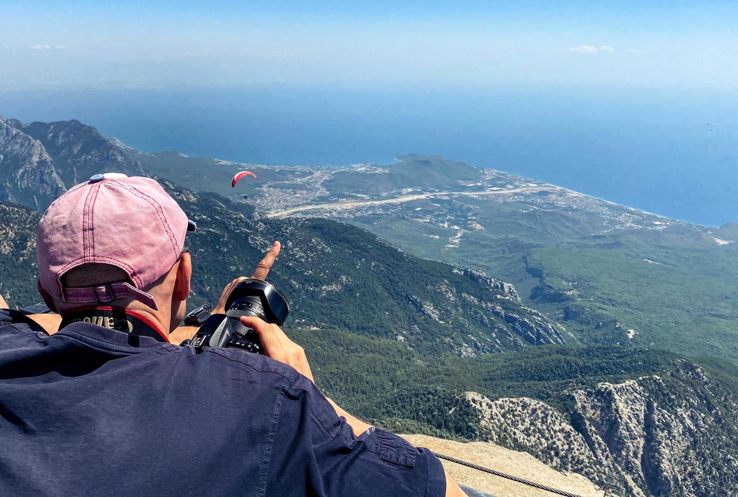 tourists on the observation deck. a man in a white cap photographs a bird's eye view. in his hand he has a big black camera with a lens photo