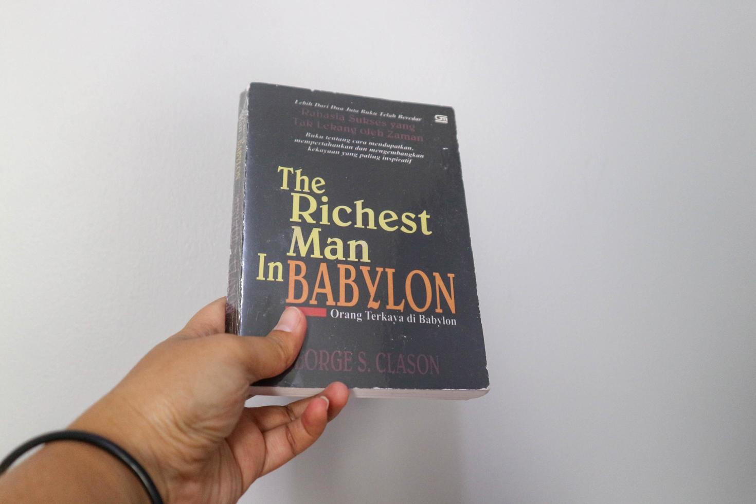 West Java, Indonesia on July 2022. A hand is holding a novel The Richest Man in Babylon. photo