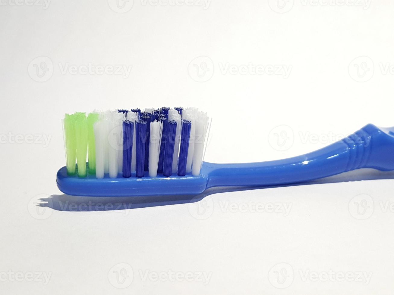 Isolated white photo of a plastic toothbrush that has been used several times. This toothbrush has a blue handle.