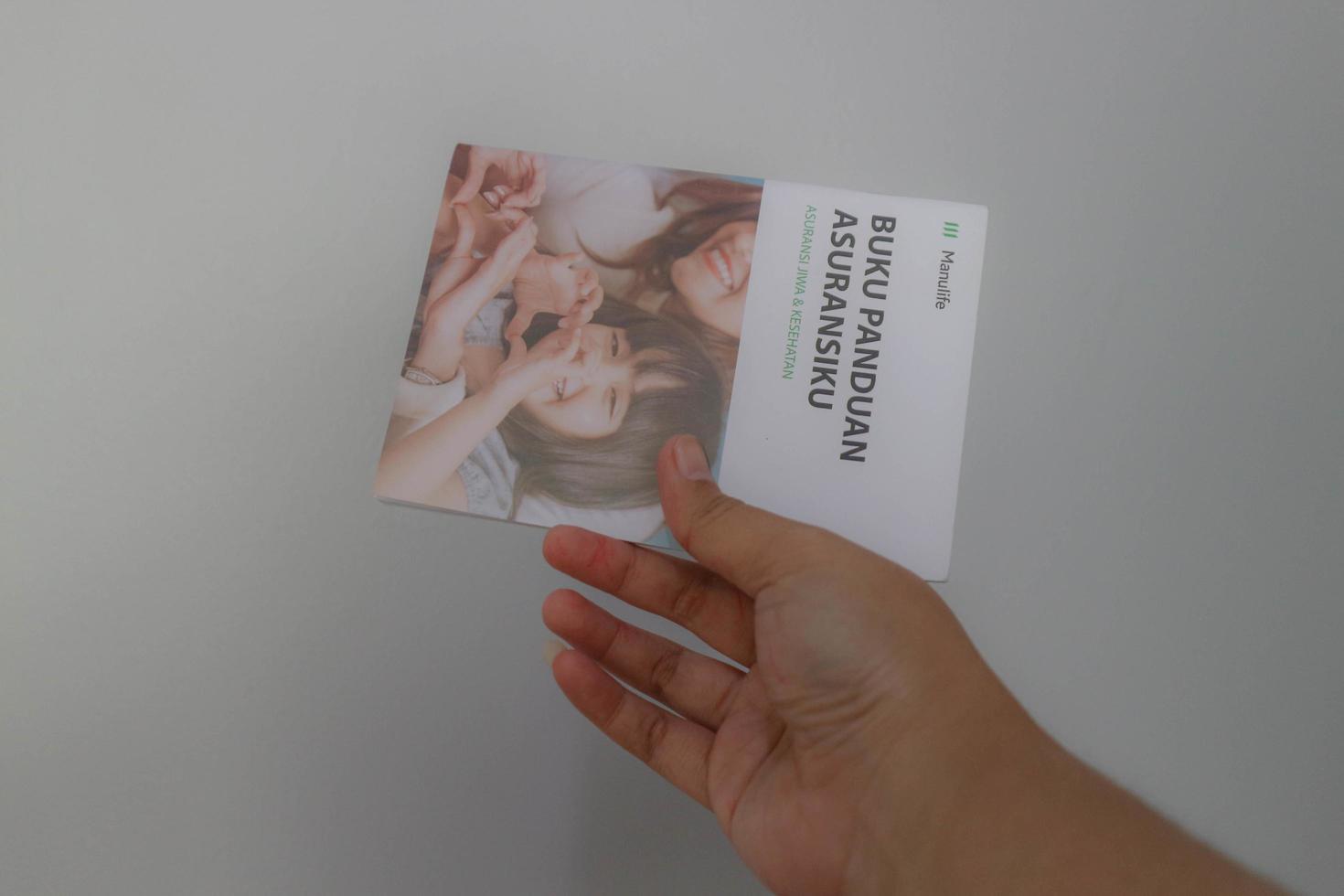 West Java, Indonesia on July 2022. A hand holding Manulife's Insurance Handbook for life and health insurance photo