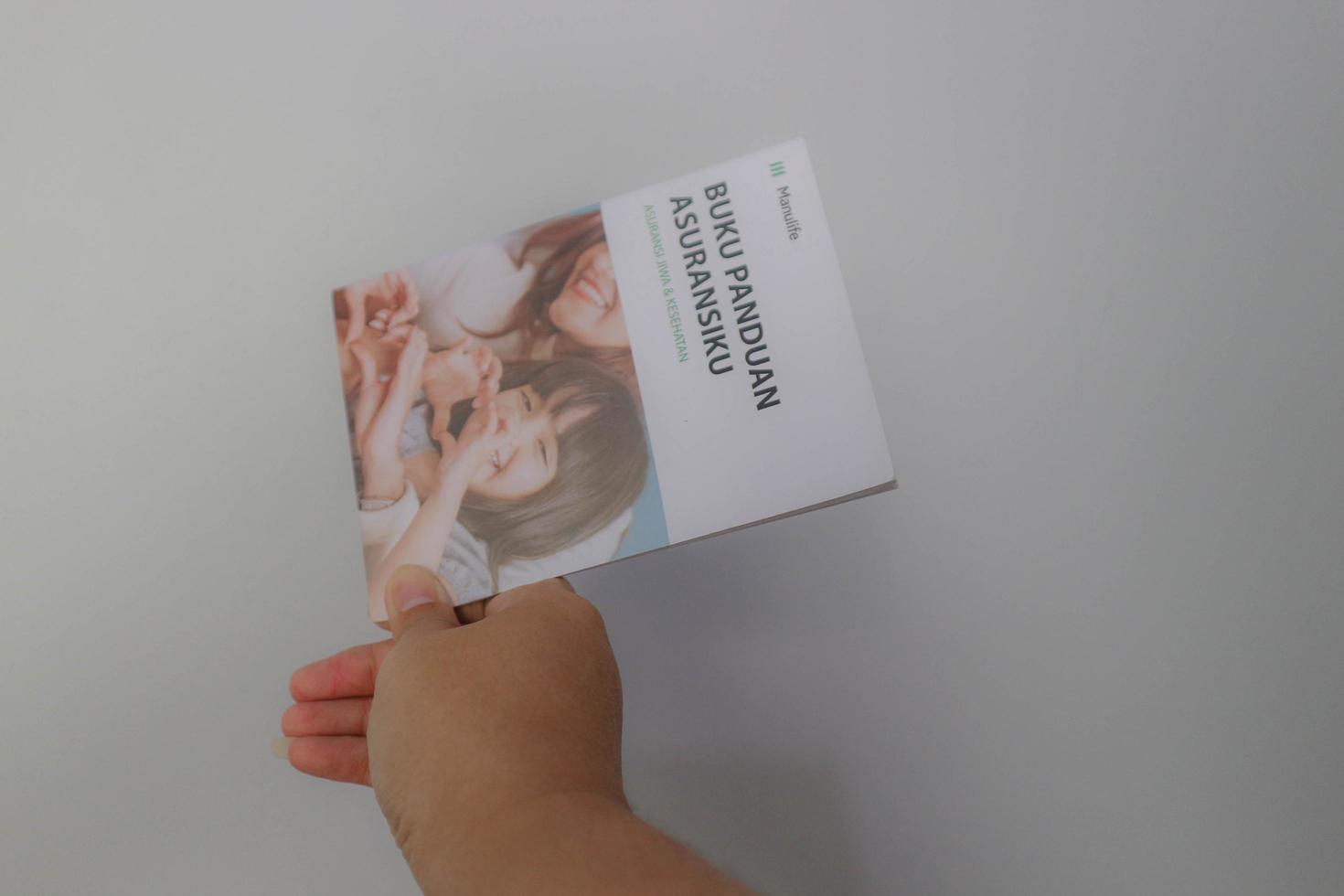 West Java, Indonesia on July 2022. A hand holding Manulife's Insurance Handbook for life and health insurance photo