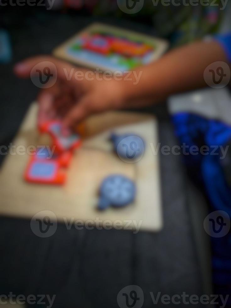 Defocused blurry shot of a boy's hand holding a wooden puzzle photo