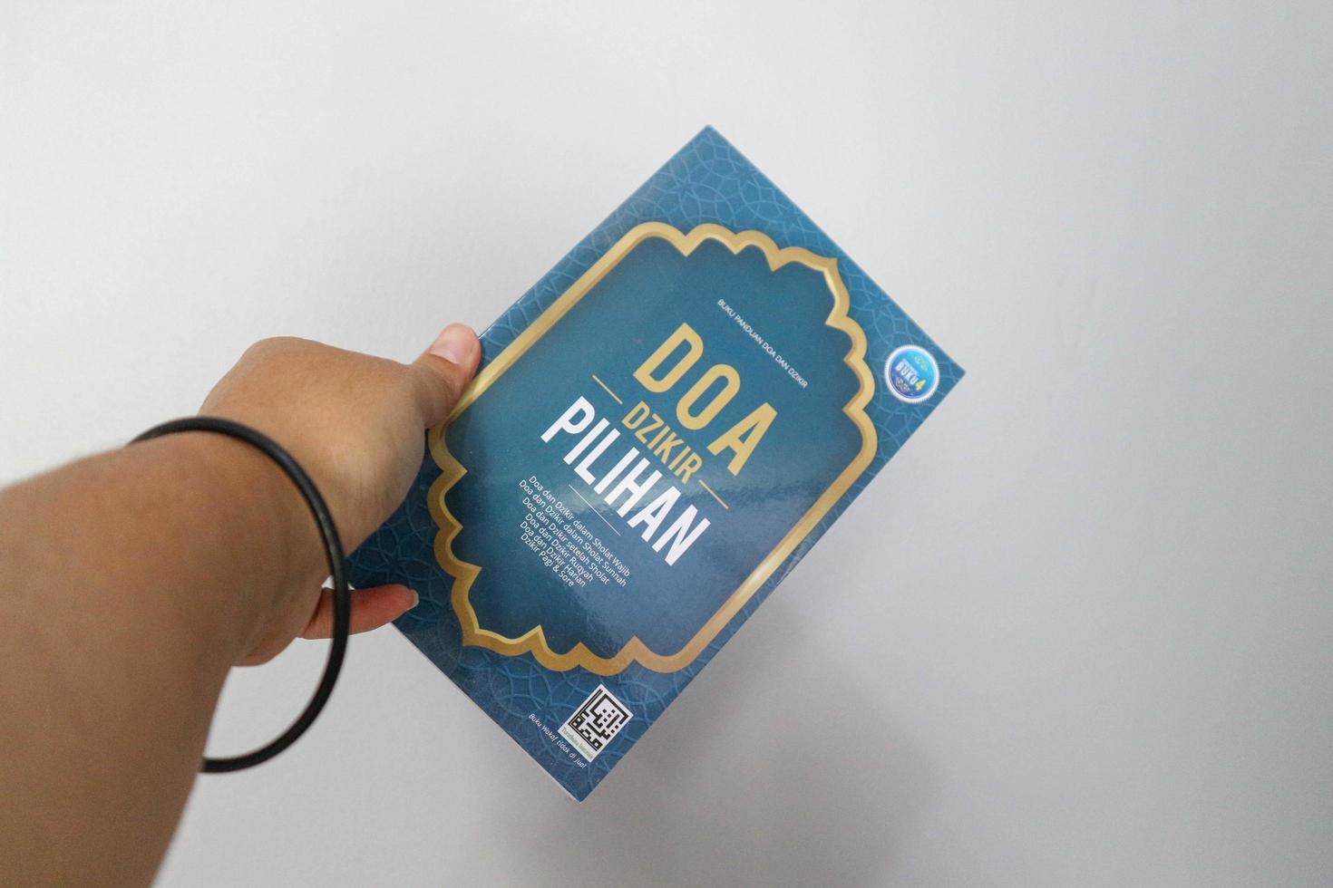 West Java, Indonesia on July 2022. A hand is holding a book of selected prayer and dhikr guides for Muslims. photo