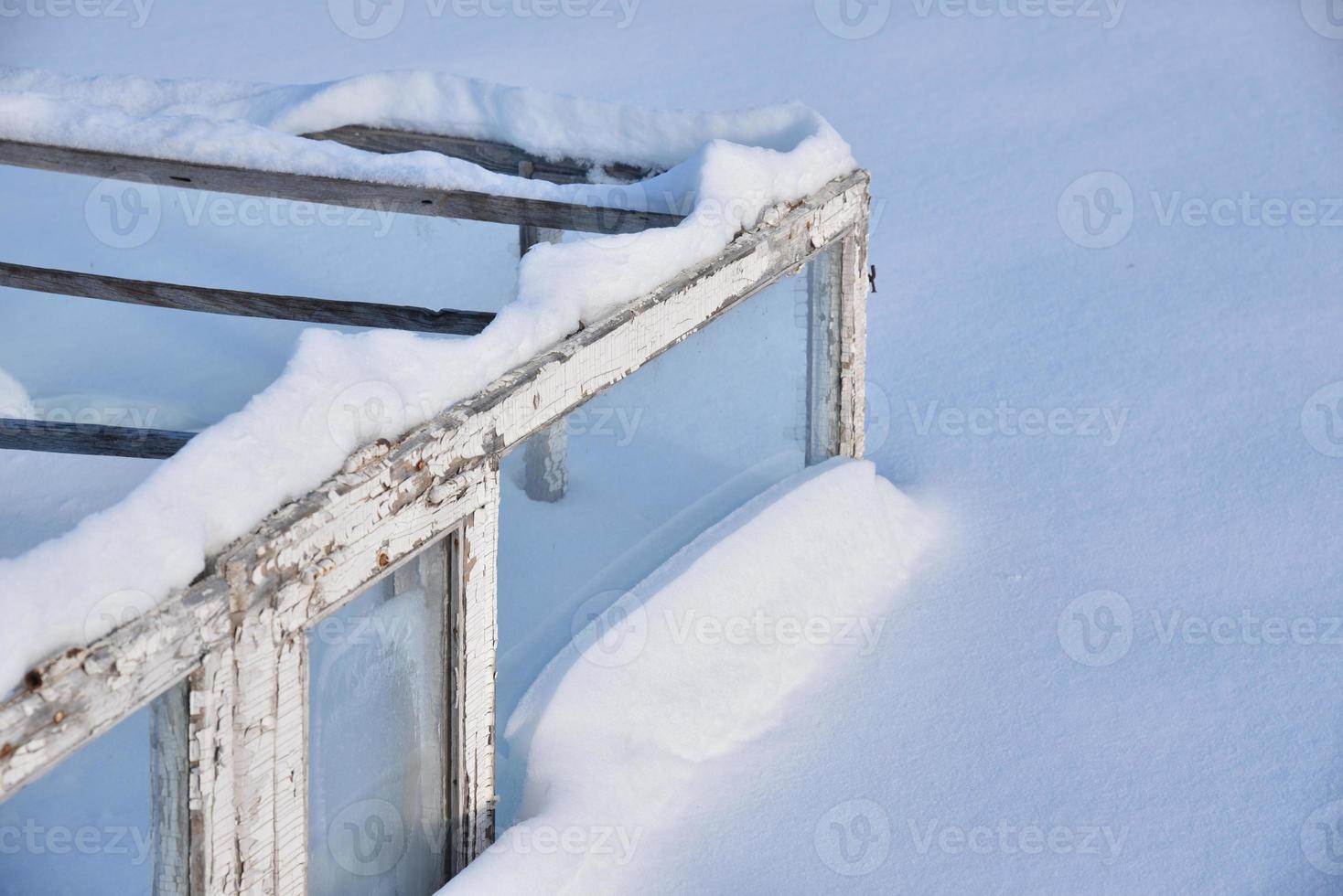 Wooden boxes in winter in the snow. A small greenhouse in snowdrifts in winter. photo