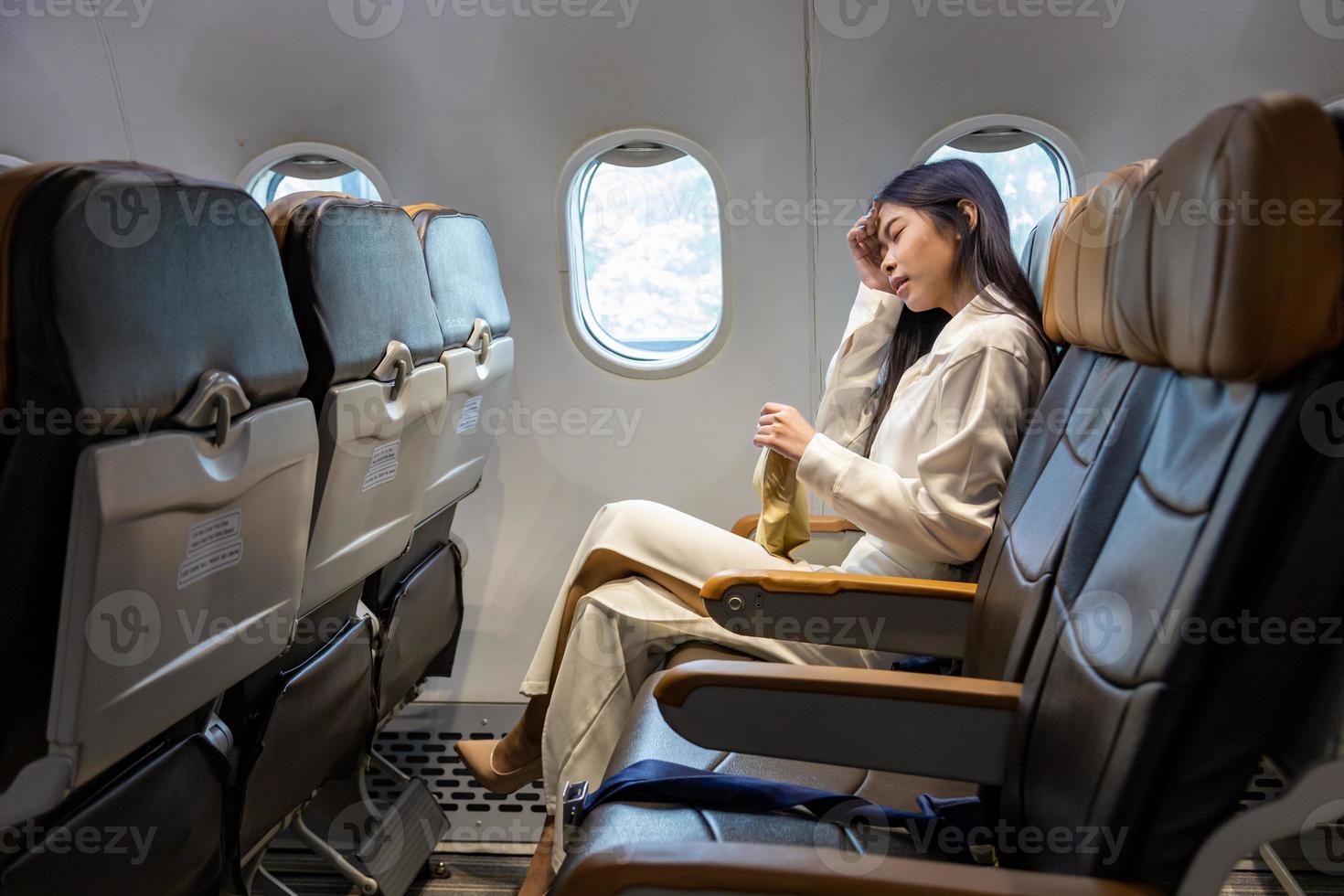 la mujer asiática se siente mareada y se aferra a la bolsa de vómitos durante el vuelo en el avión debido al movimiento y la enfermedad del viaje que causan mareos por aerofobia y transporte foto