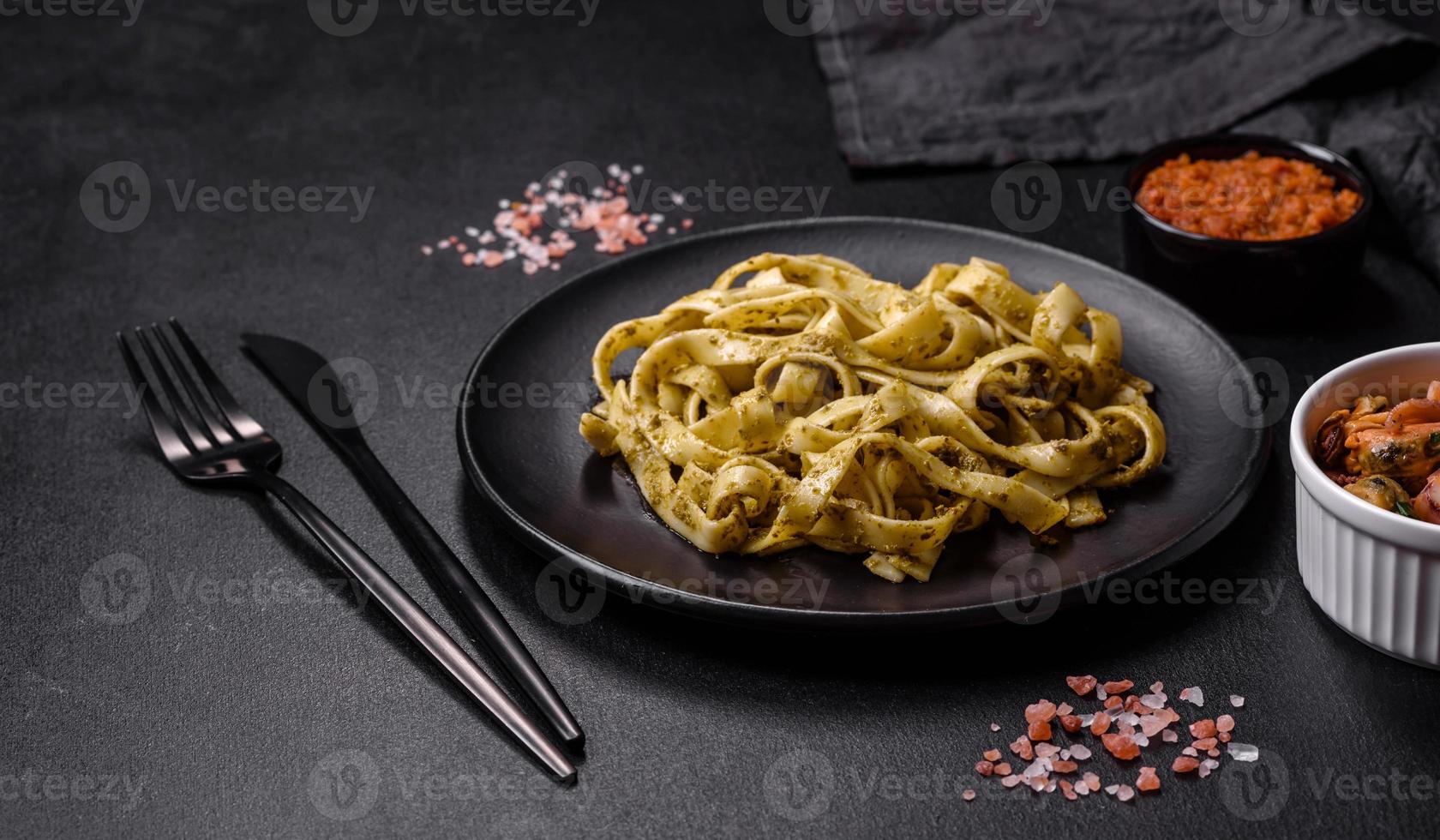deliciosa pasta fresca con salsa pesto y marisco en un plato negro foto