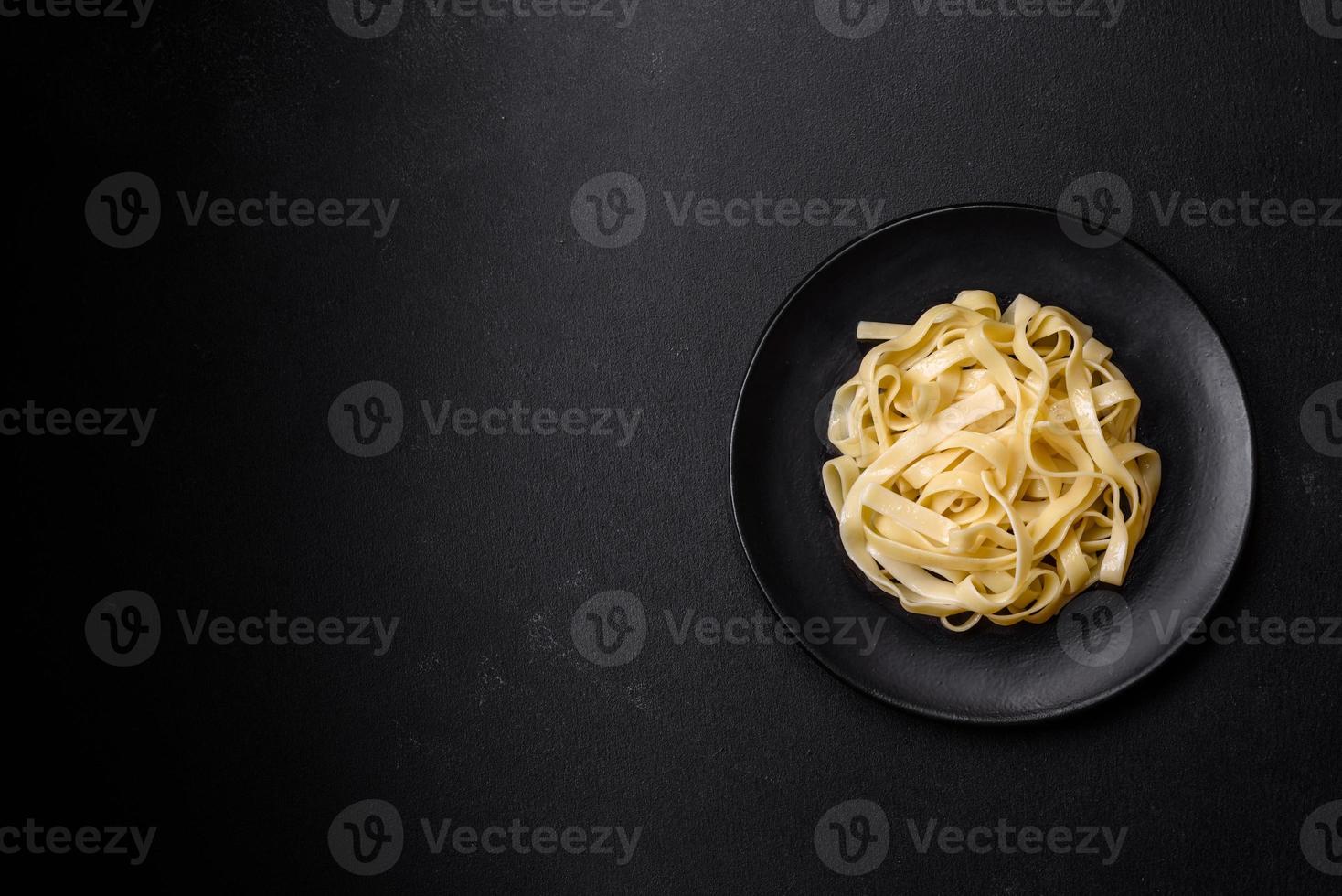 Delicious fresh pasta with pesto sauce and seafood on a black plate photo