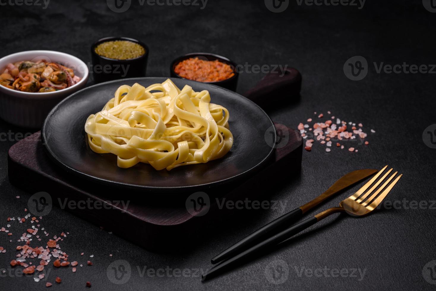 Delicious fresh pasta with pesto sauce and seafood on a black plate photo