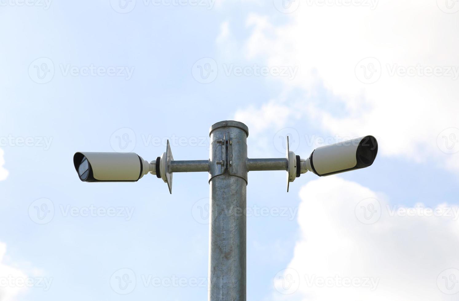 cámaras de vigilancia pública montadas en un poste con fondo de cielo azul foto