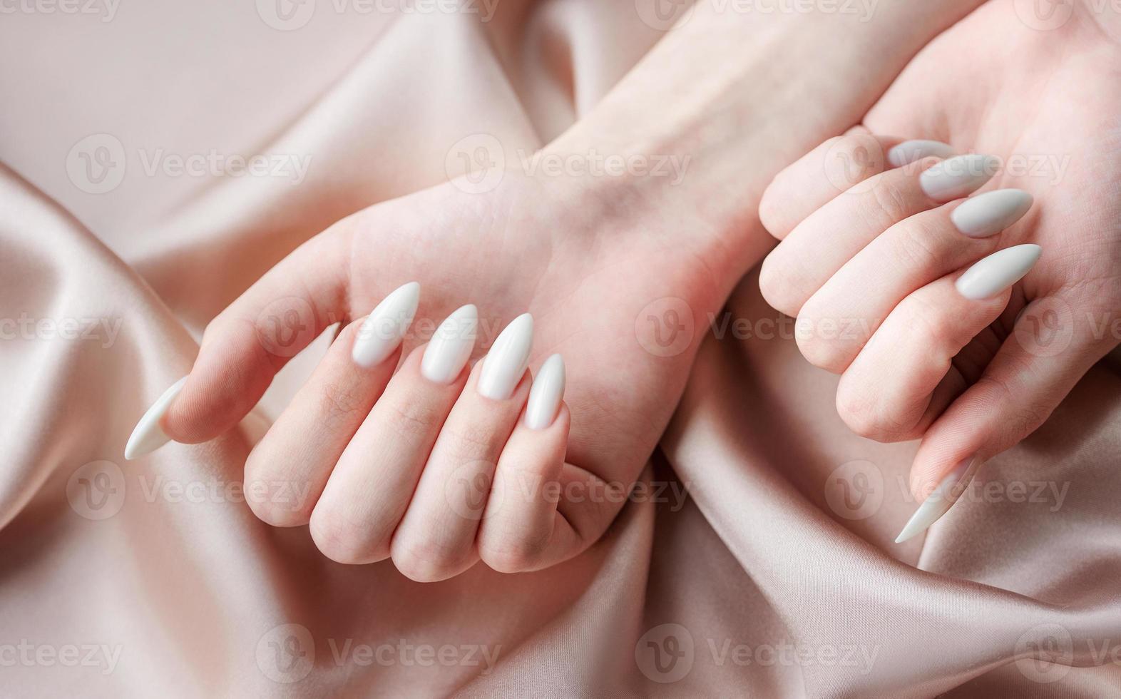 Hands of a young woman with white manicure on nails photo