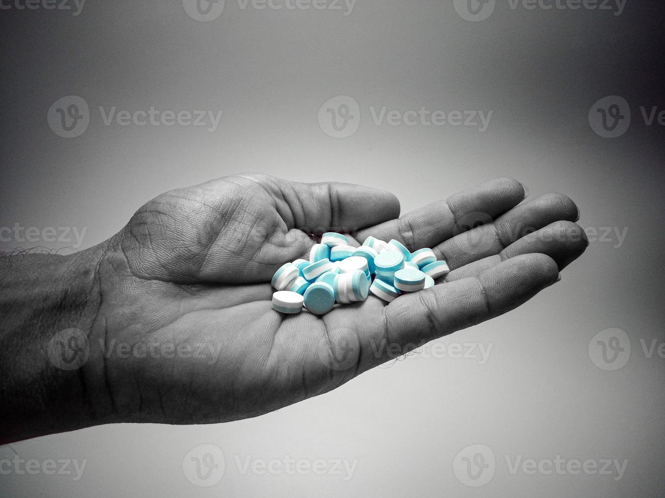 Blue and white pills in black and white hand. Depression concept. Suicide. Stress. Death. photo