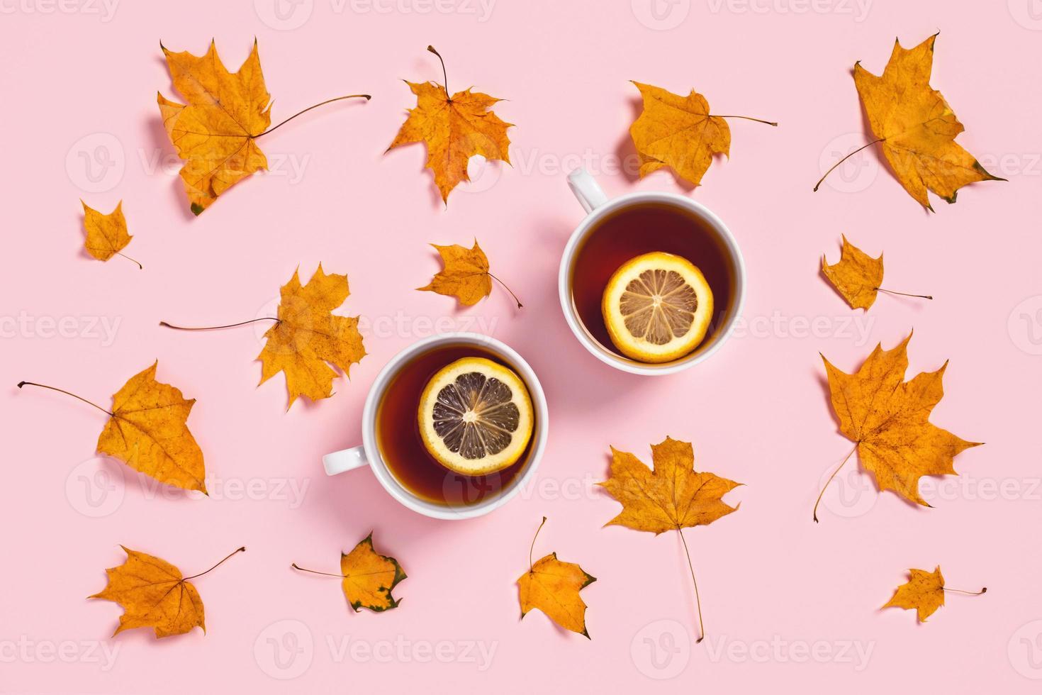 Cozy autumn composition. Two tea cups with slices of lemon and maple leaves. photo