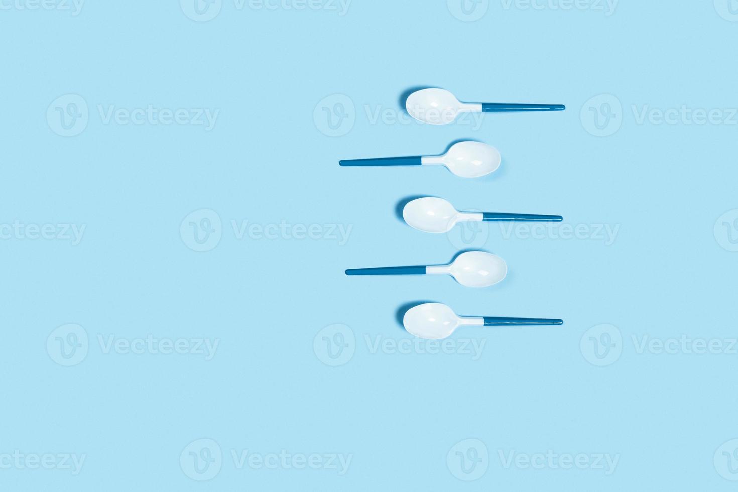 White plastic spoons on blue background. photo