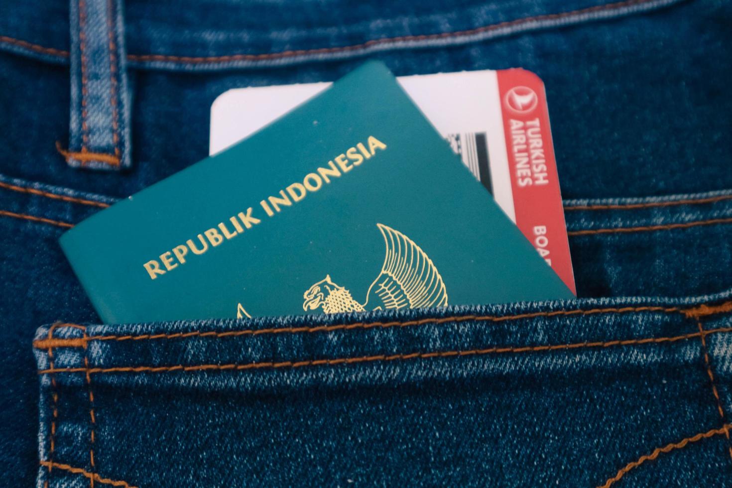 Indonesia in July 2022. An Indonesian passport and a Turkish Airlines boarding pass in a jeans pocket. photo