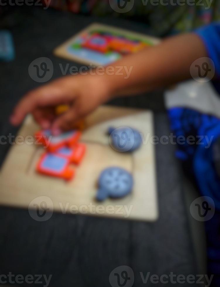 Defocused blurry shot of a boy's hand holding a wooden puzzle photo