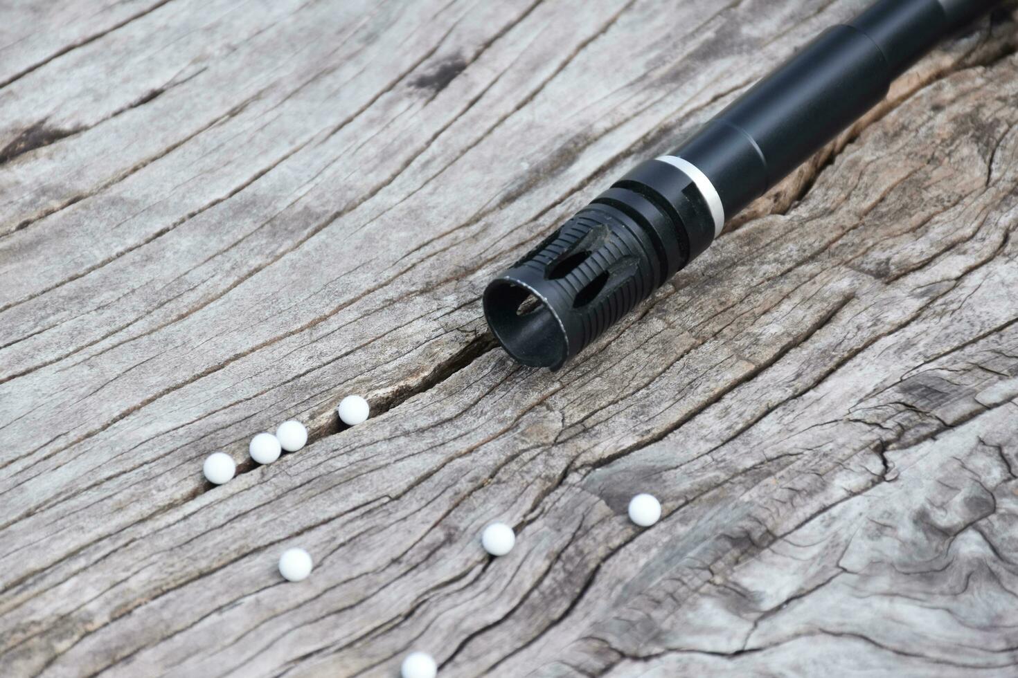 BB gun or airsoft gun muzzle and white bullets on wooden plank, soft and selective focus. photo