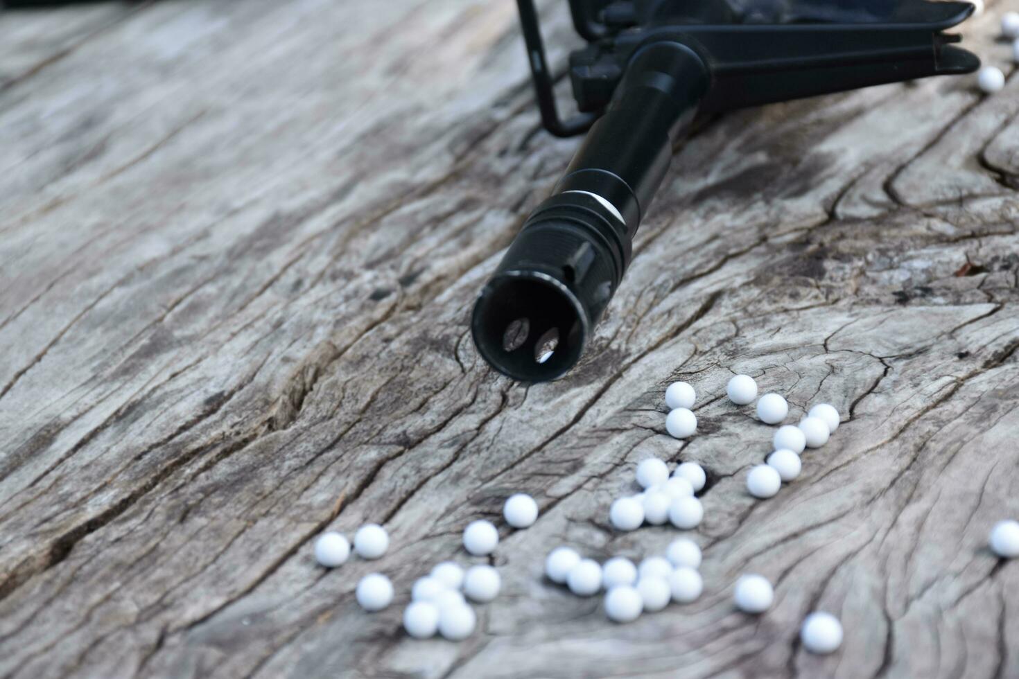 BB gun or airsoft gun muzzle and white bullets on wooden plank, soft and selective focus. photo