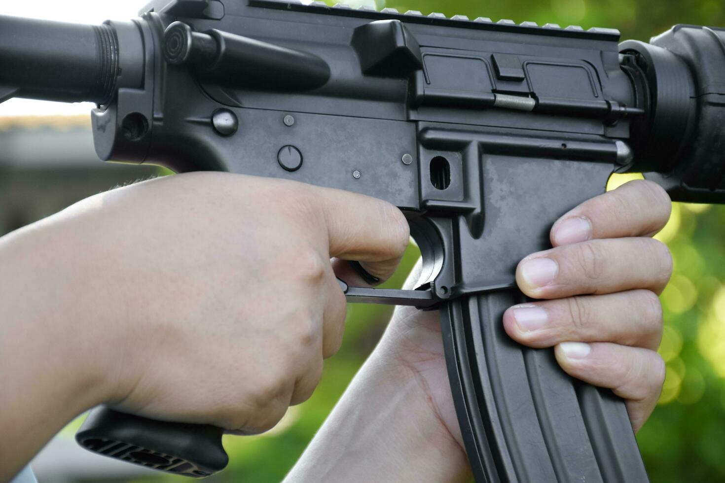 Airsoft Gun or BB Gun holding in hands of shooter while aiming to the destination target at the bb gun or airsoft gun training camp, soft and selective focus, concept for freetimes and outdoor hobby. photo