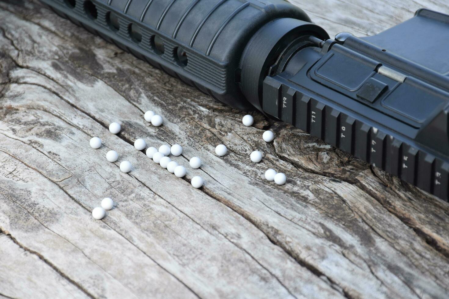 BB gun or airsoft gun muzzle and white bullets on wooden plank, soft and selective focus. photo