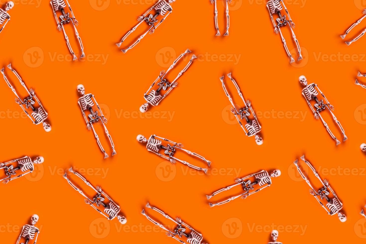 Halloween pattern of skeletons on orange background. photo