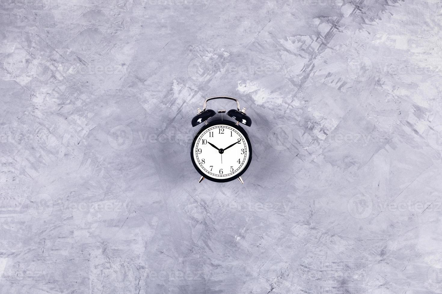 Black clock on grey concrete background. photo