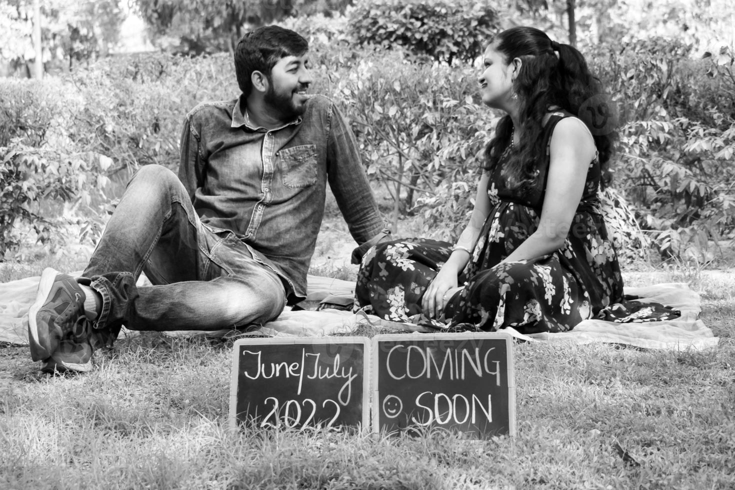 pareja india posando para una sesión de fotos de maternidad. la pareja está posando en un césped con hierba verde y la mujer está faluntando su panza en el jardín lodhi en nueva delhi, india