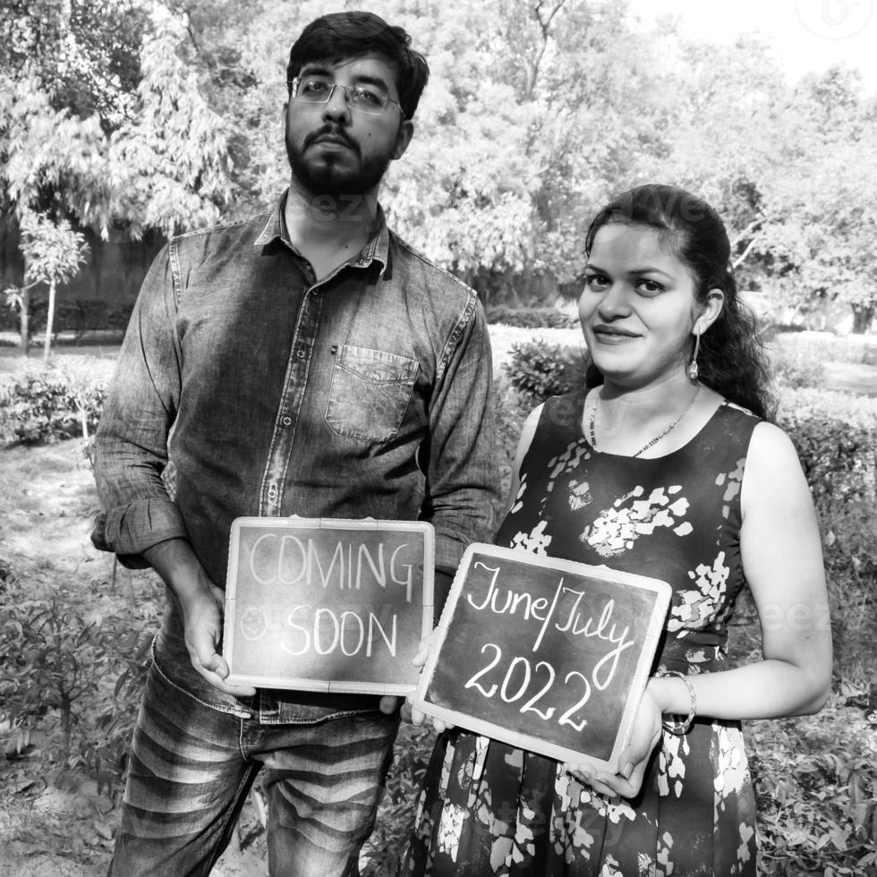 Indian couple posing for maternity baby shoot. The couple is posing in a lawn with green grass and the woman is falunting her baby bump in Lodhi Garden in New Delhi, India photo