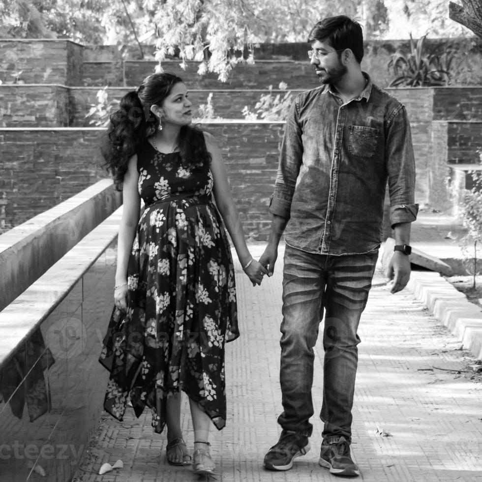 Indian couple posing for maternity baby shoot. The couple is posing in a lawn with green grass and the woman is falunting her baby bump in Lodhi Garden in New Delhi, India photo